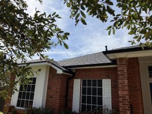 dark color gutters on red brick home with white shutters